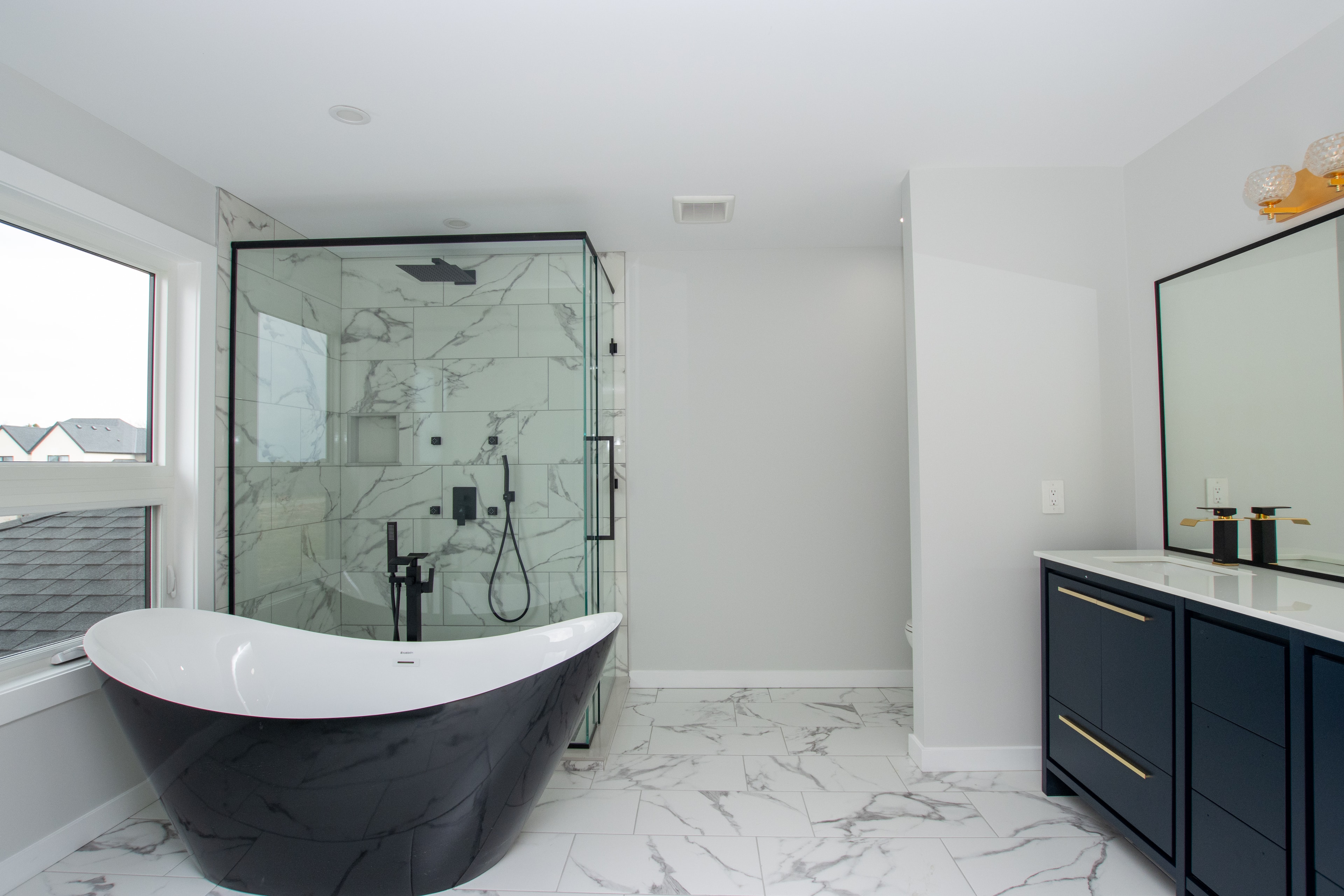 Ensuite with black soaker tub, glass shower and navy vanity