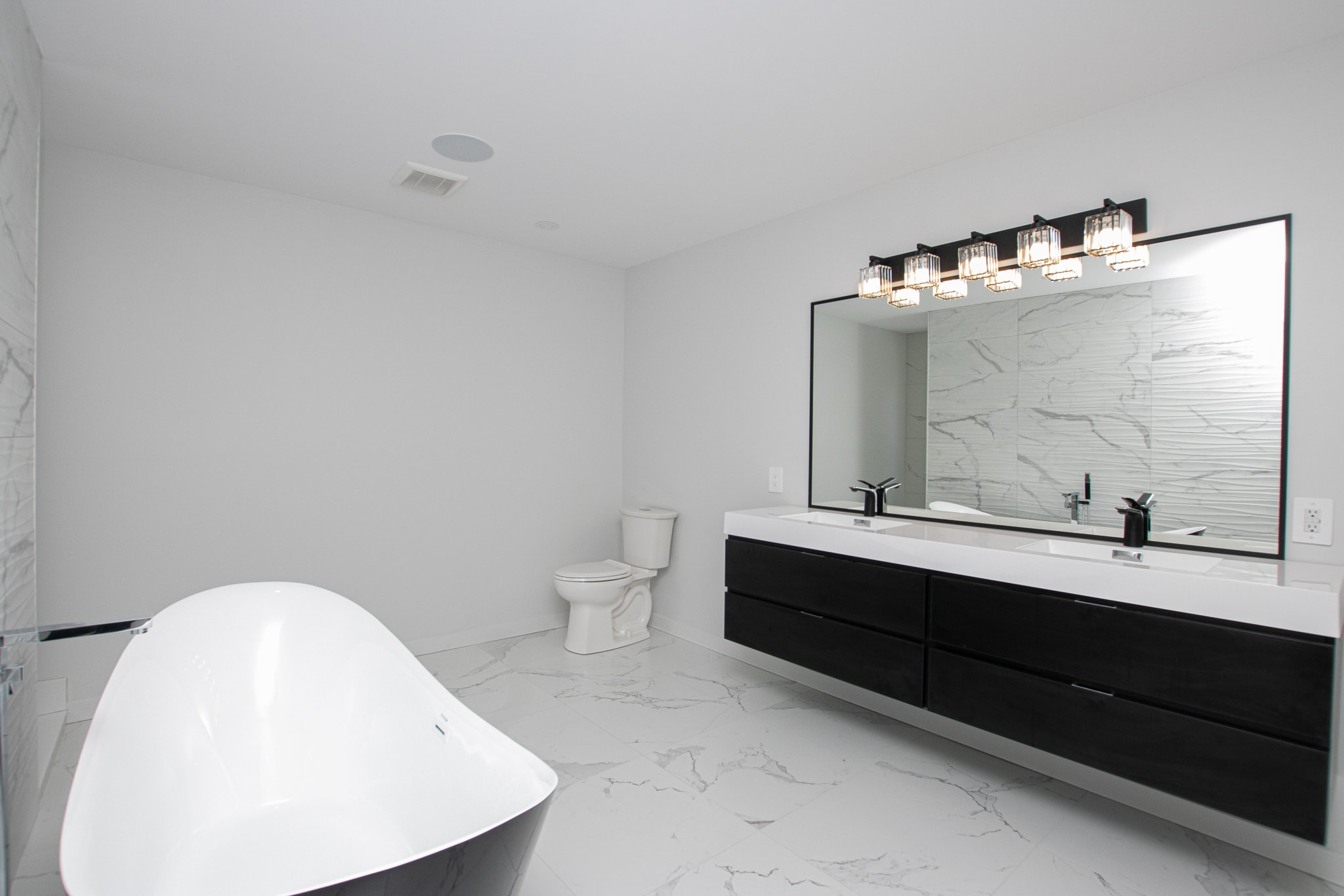 White kitchen with long island and dark accent wall beyond