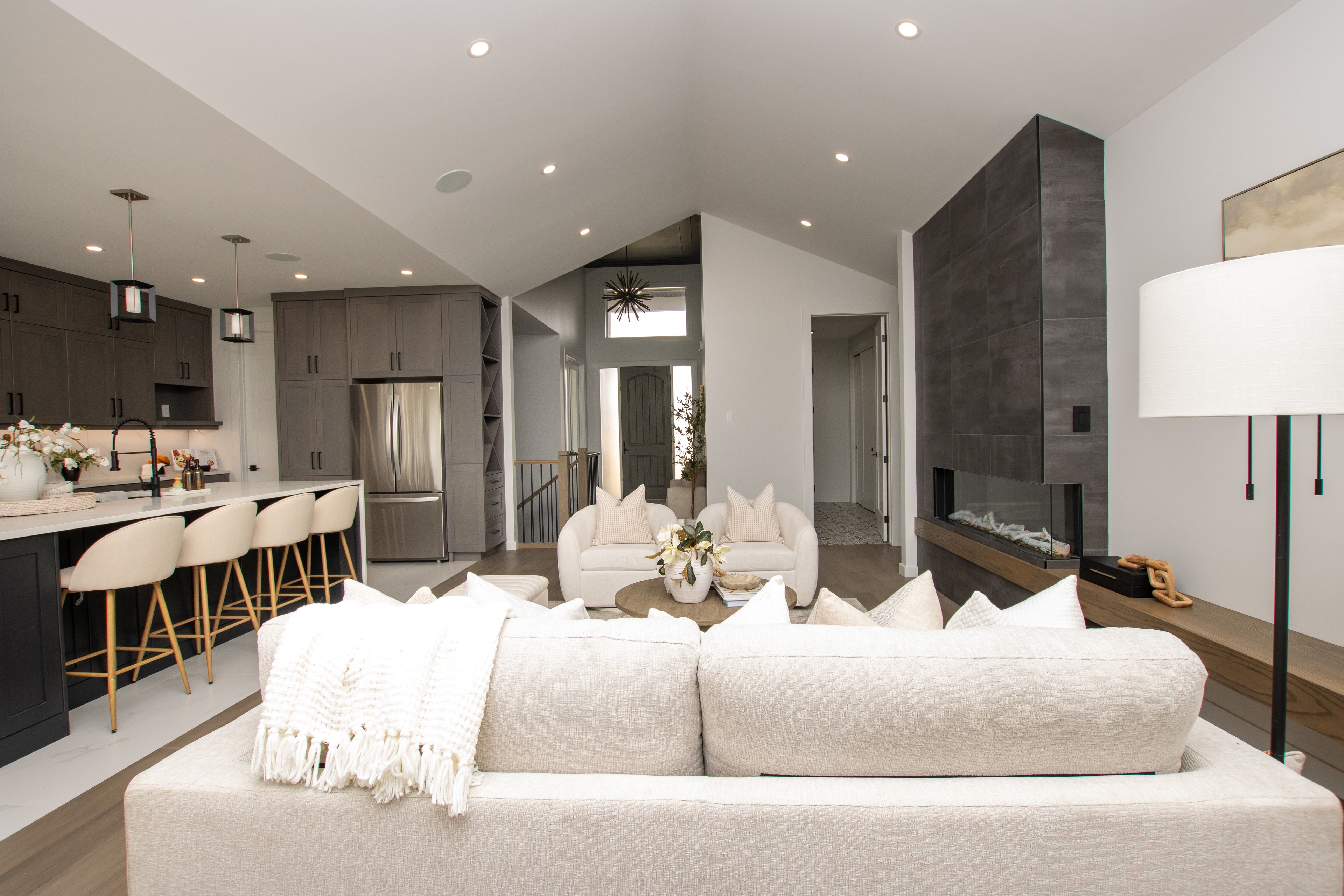 Open concept living room with dark kitchen, vaulted ceiling and fireplace