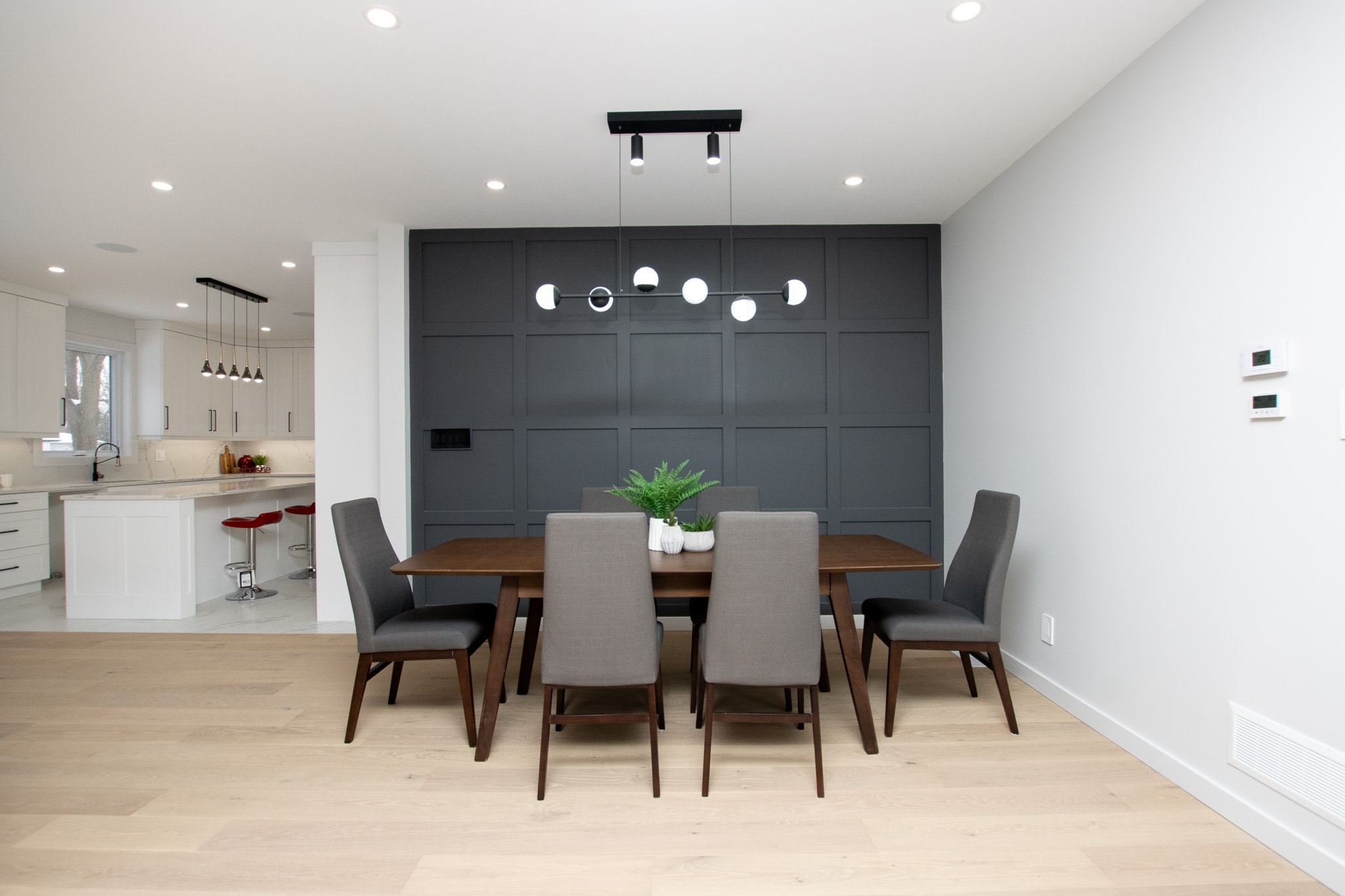 Dining room with dark accent wall and modern chandelier